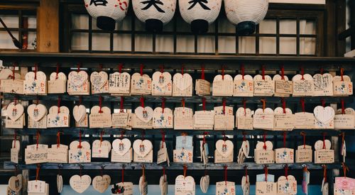 Free Heart-shaped wooden ema tablets with handwritten wishes hanging at a Japanese shrine. Stock Photo