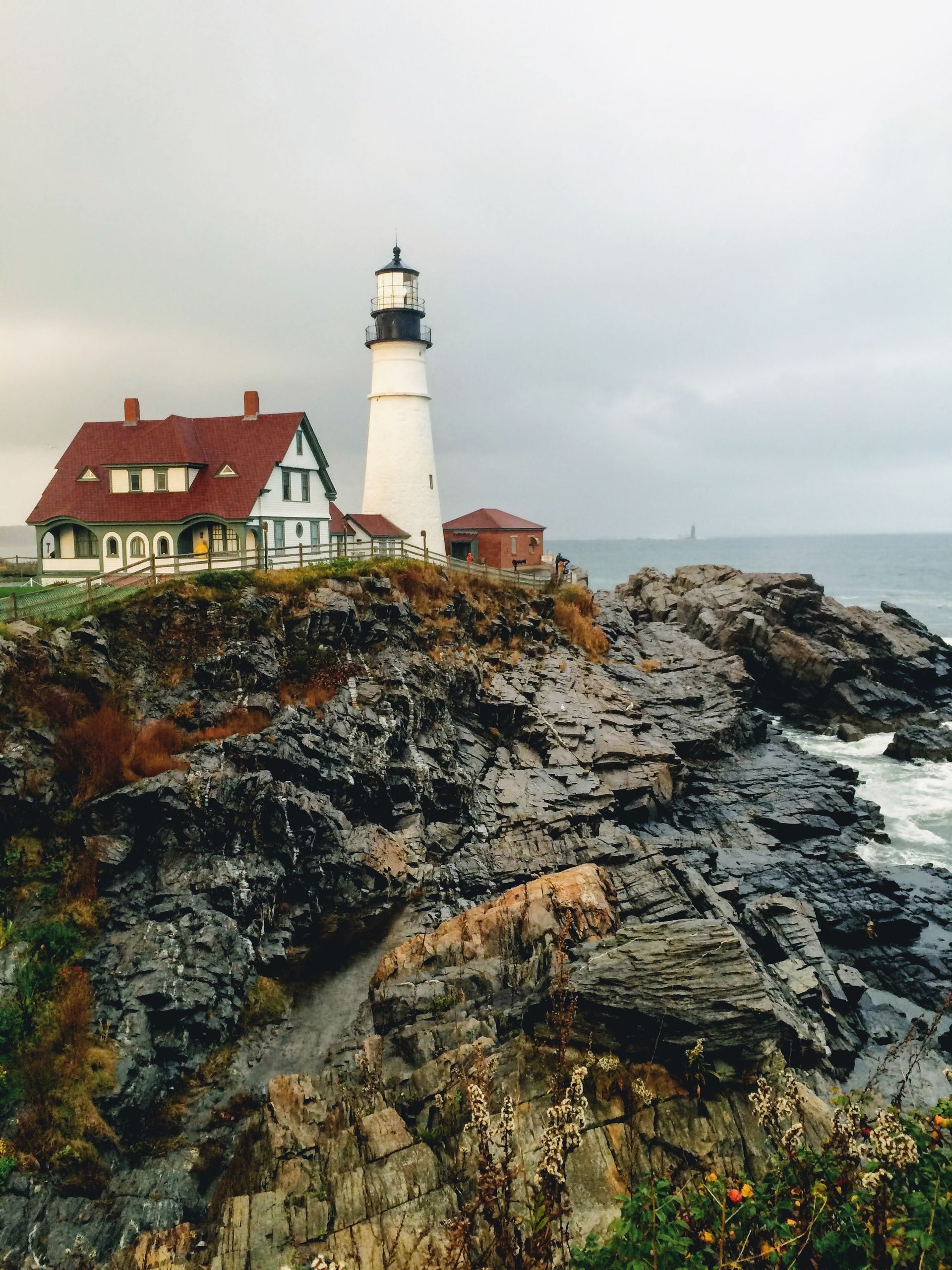 Scenic view of Portland Head Light in Maine against dramatic rocky cliffs and ocean.