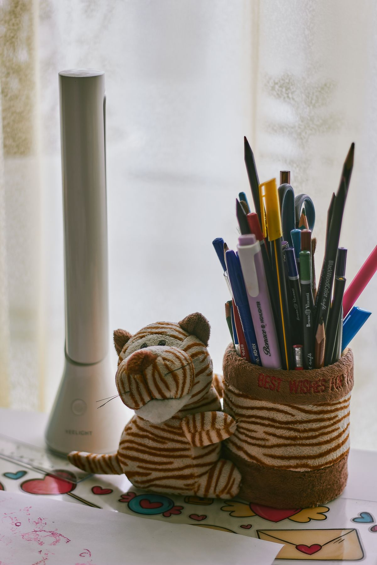 A child's desk with colorful stationery and a plush toy