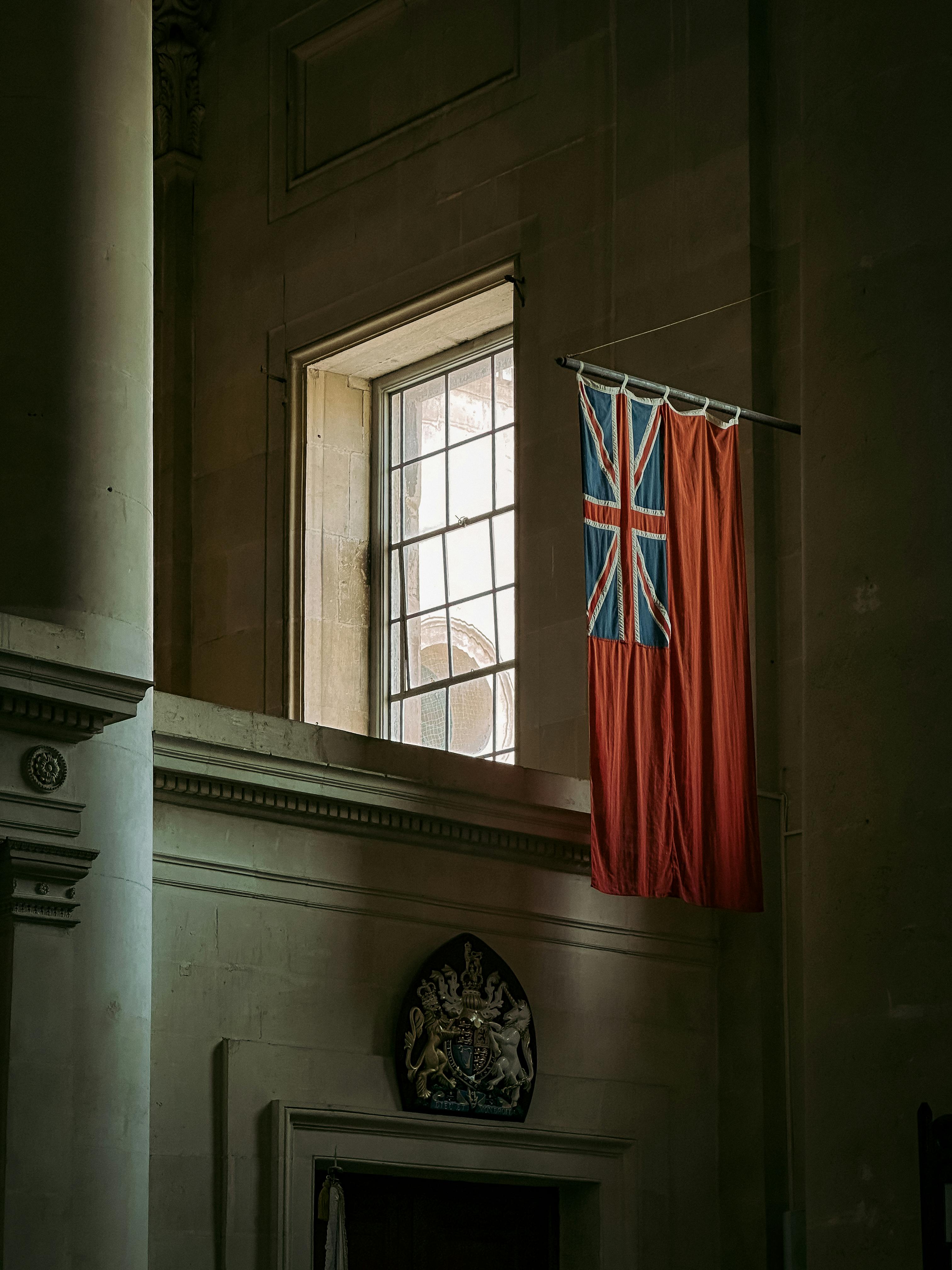 A Union Jack flag hanging inside a sunlit cathedral in Valletta, Malta.