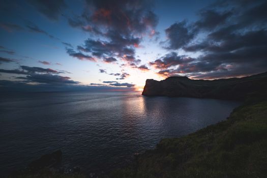 Majestic sunset over the ocean with dramatic cliffs and colorful clouds creating a picturesque view.