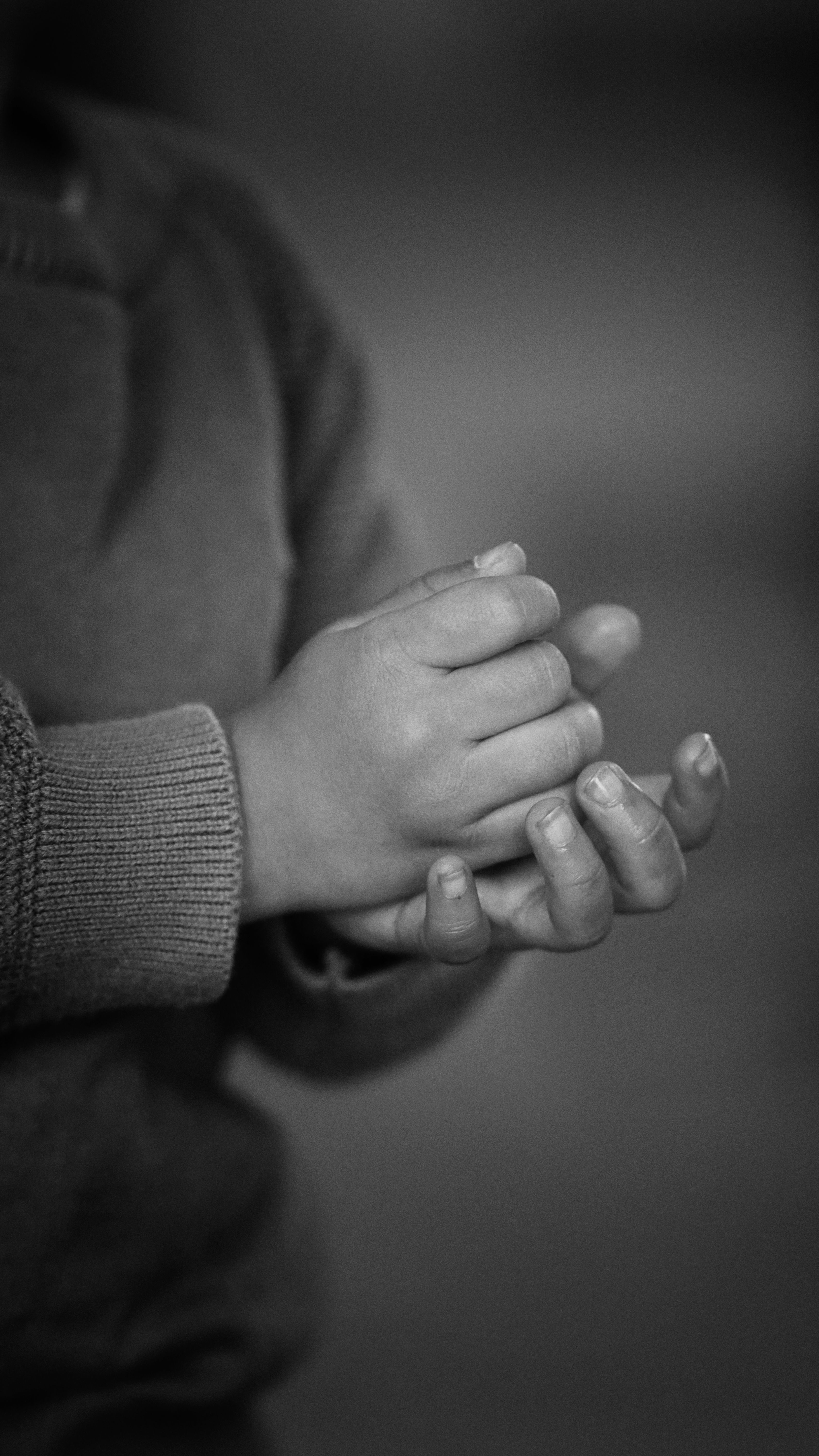 A monochrome photo depicting a child's hands clasped together, highlighting innocence and emotion.
