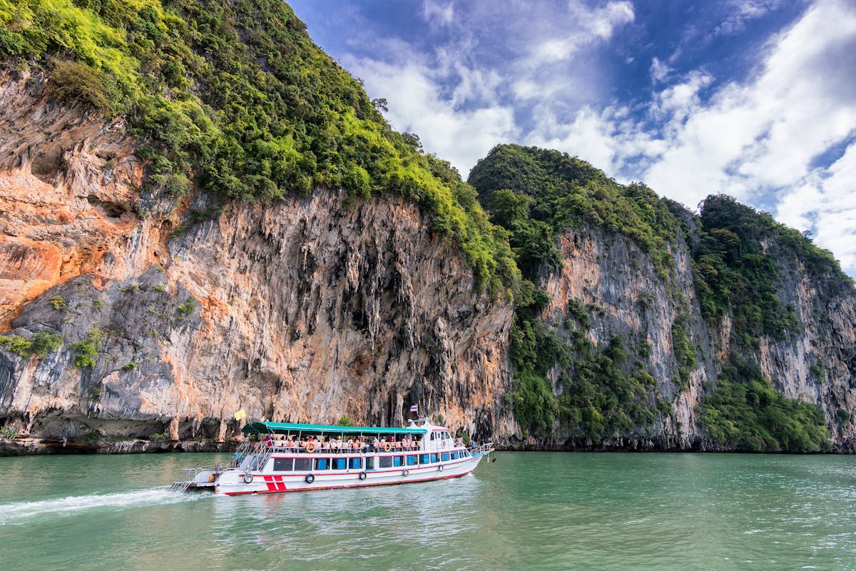 People on Ship Traveling on Water Beside Land in Thailand