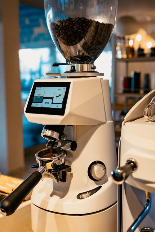 Free High-end coffee grinder with touchscreen in a cozy café setting, perfect for coffee enthusiasts. Stock Photo