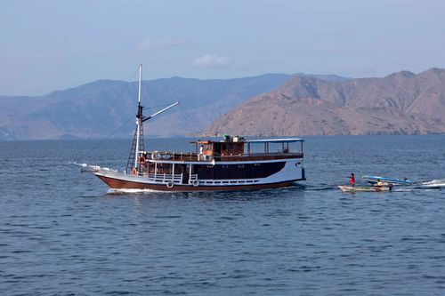 Free A classic Indonesian Phinisi boat sails near Komodo Island, surrounded by serene waters and mountainous landscapes. Stock Photo