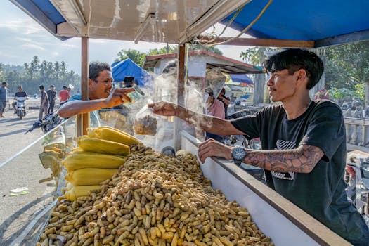 A street vendor in Aceh, Indonesia selling steamed corn and peanuts to a customer.