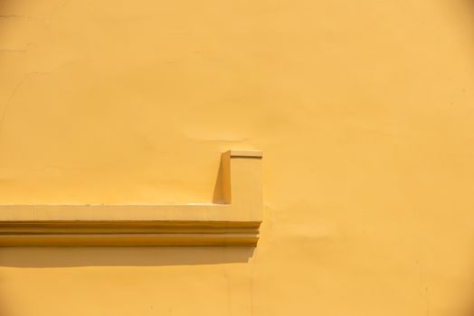 Abstract view of a minimalist yellow stucco wall with architectural detail, provides a soothing backdrop.