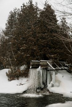 冬日景象宁静，森林里有一挂冰瀑，四周白雪覆树