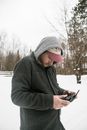一名男子身着冬季装备，在雪地中操作无人机控制器