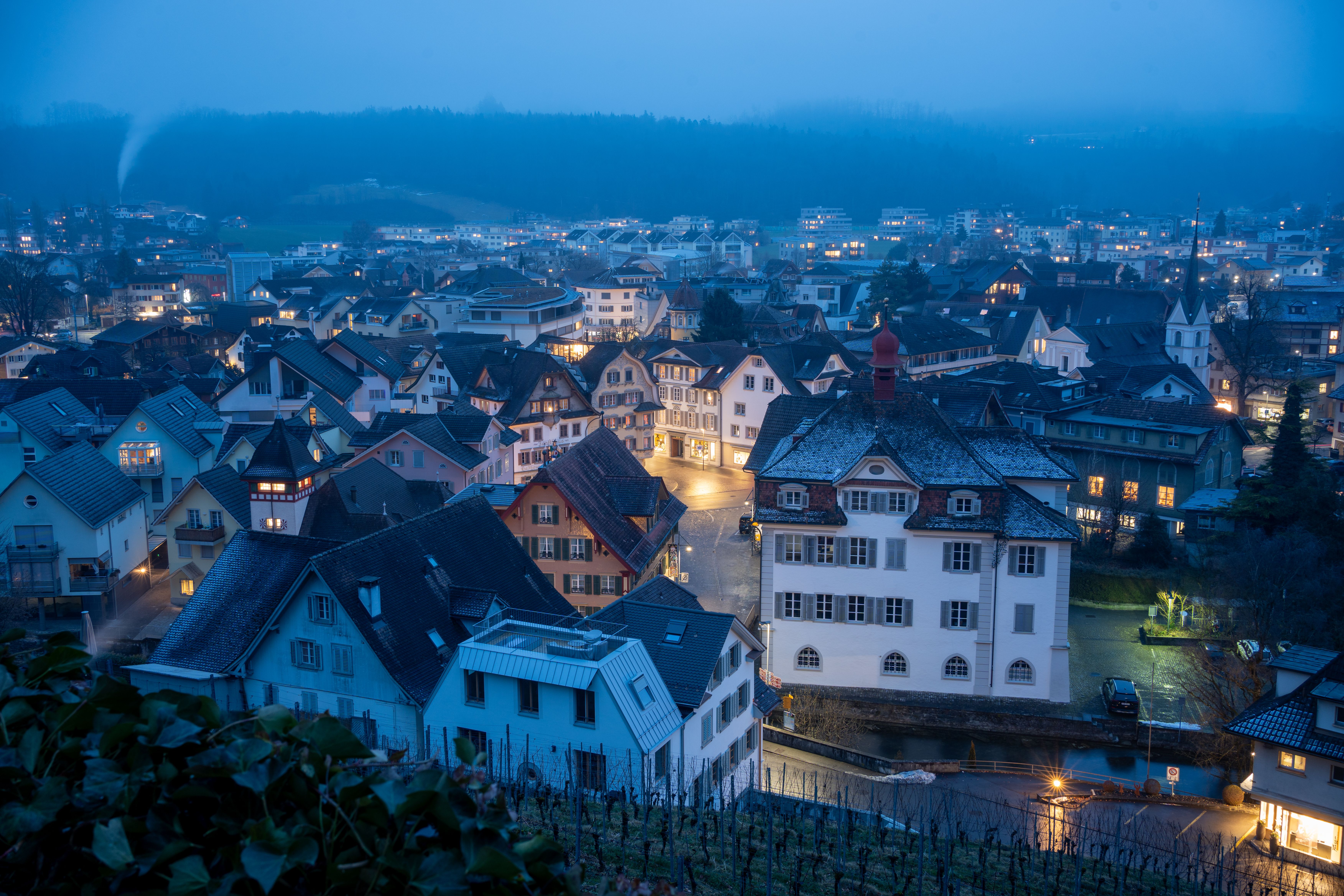 A picturesque view of a Swiss village at twilight during winter, showcasing traditional rooftops.