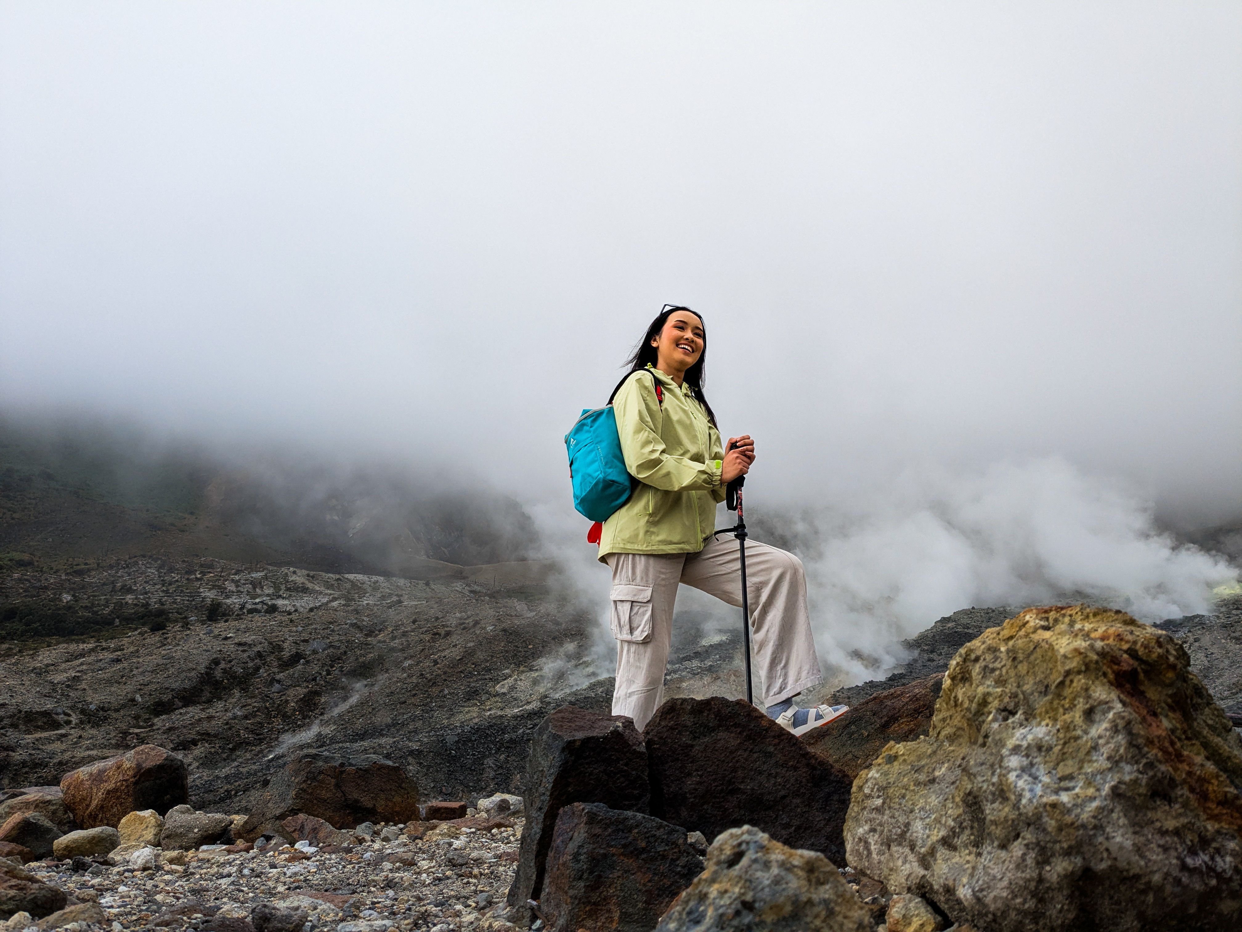 A woman enjoying a mountain hike amidst clouds and rocky terrain, capturing the essence of adventure.