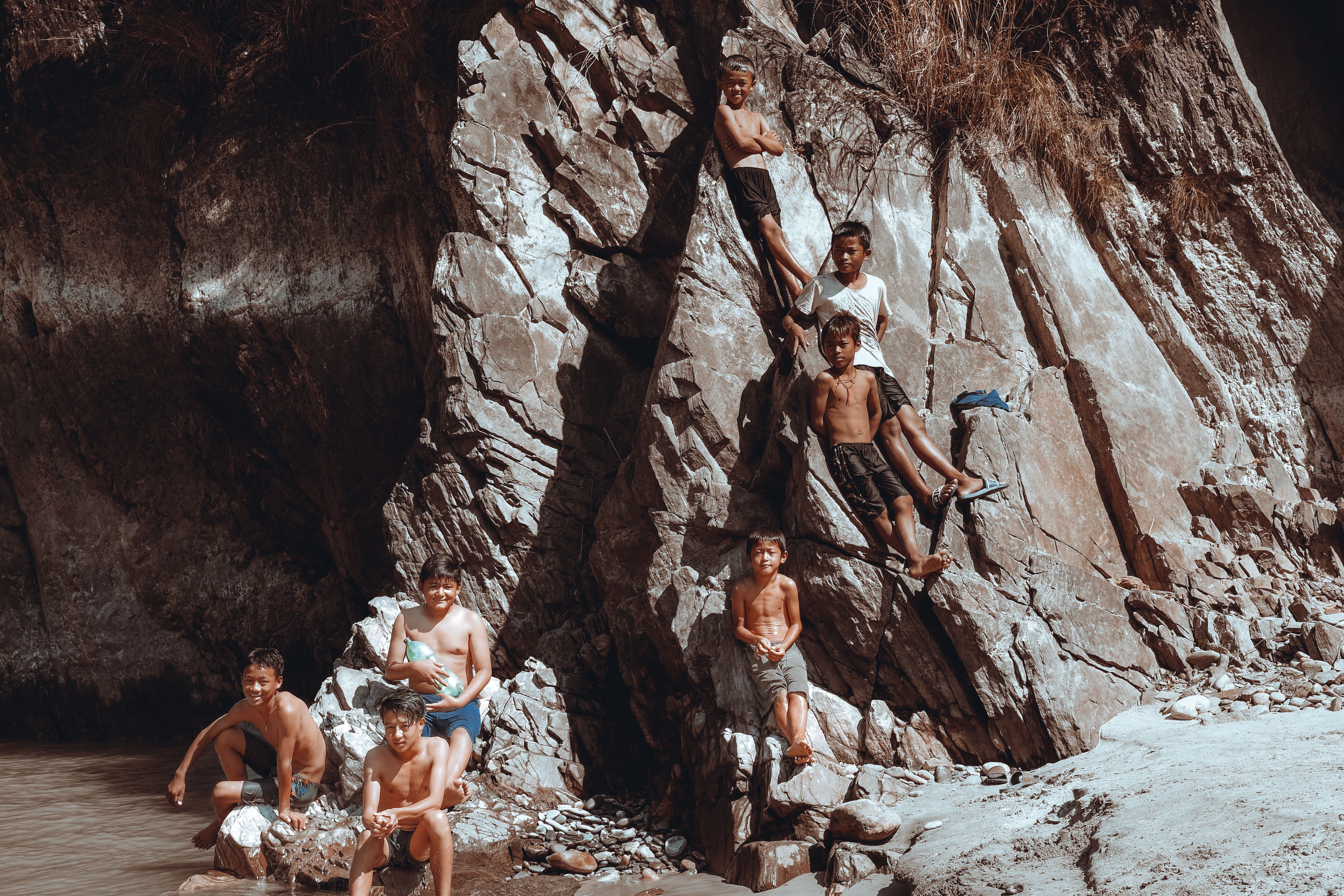 Kids climbing and playing on rocky river cliffs in Koshi Province, Nepal.