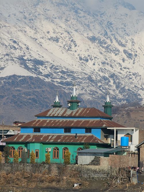 Free Colorful mosque set against snow-capped mountains, blending architectural beauty with natural splendor. Stock Photo