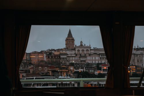 Free A captivating view of Istanbul's Galata Tower framed by curtains during twilight. Stock Photo