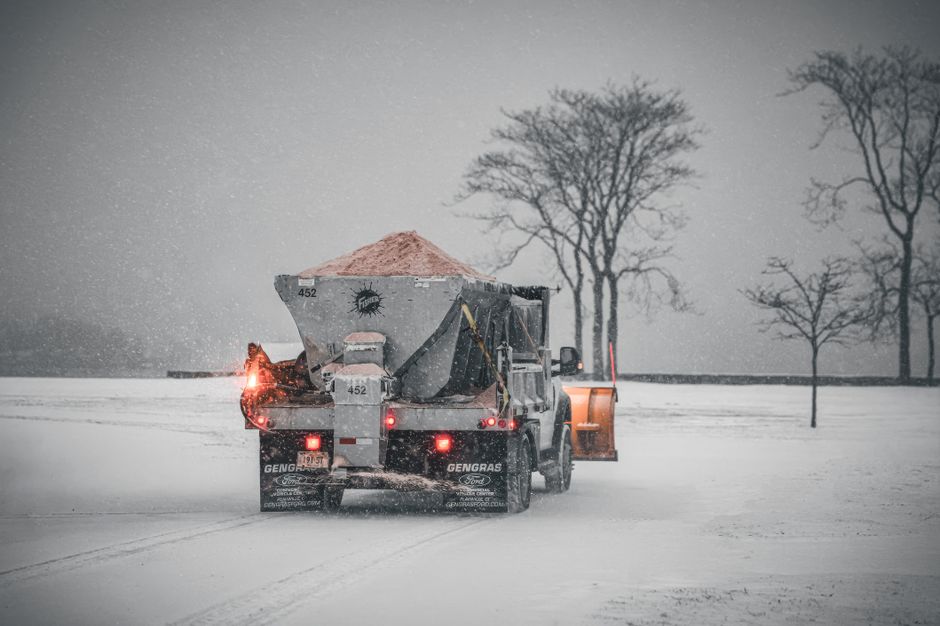 image of a salt spreader truck treating an icy parking lot at night - Professional snow plowing image of a salt spreader truck treating an icy parking lot at night - Professional snow plowing