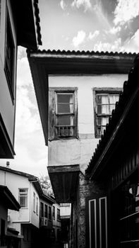 Monochrome view of historic architecture on a narrow street under a cloudy sky.