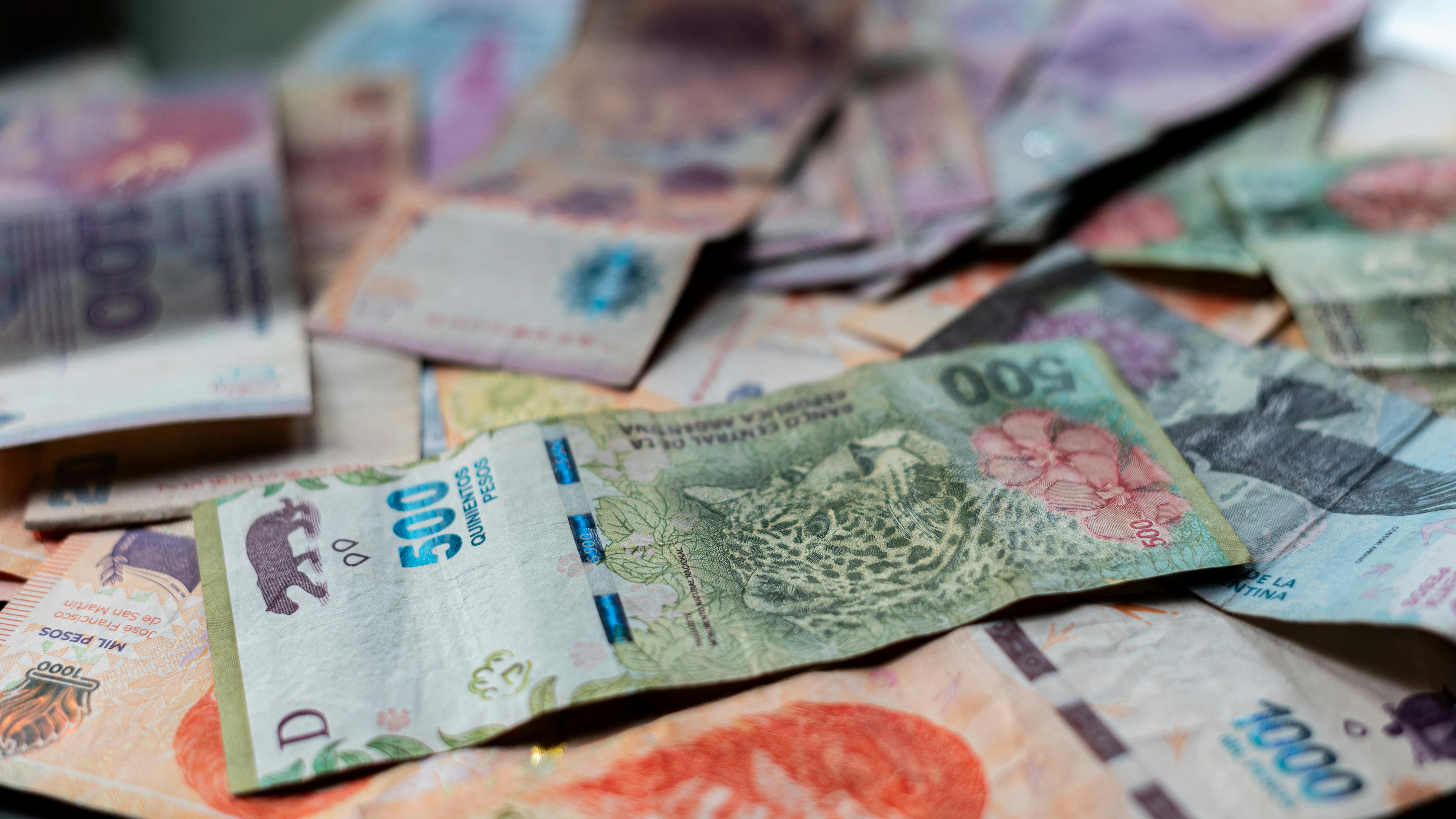 A detailed view of Argentine peso banknotes scattered on a table, showcasing various denominations.