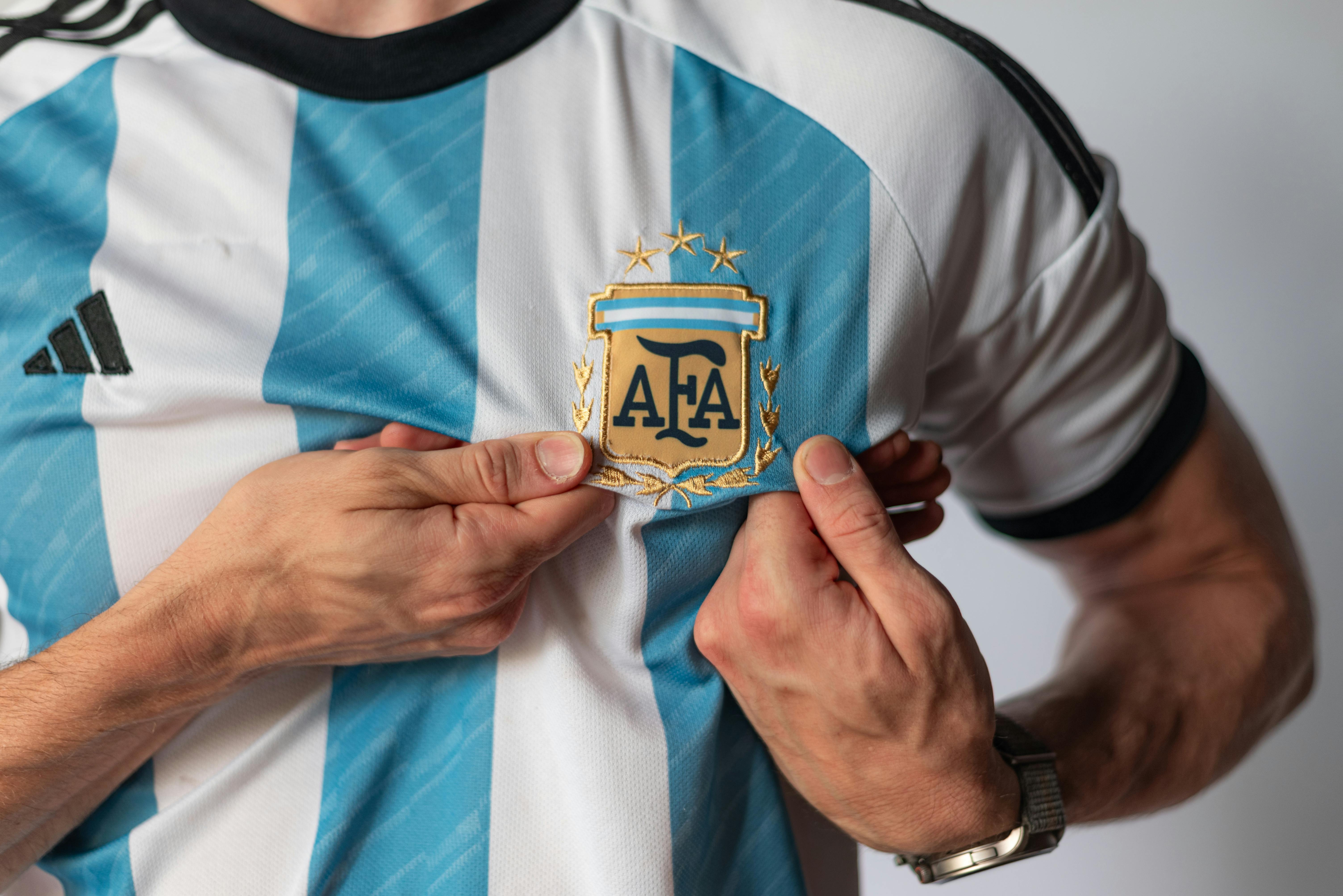 Detailed view of a person holding the emblem on an Argentina football jersey, showcasing national pride.