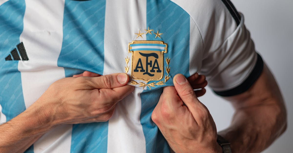 Detailed view of a person holding the emblem on an Argentina football jersey, showcasing national pride.