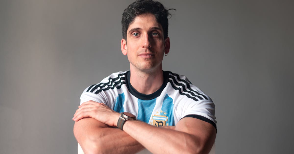 A confident man wearing the Argentine national football jersey, posing indoors.