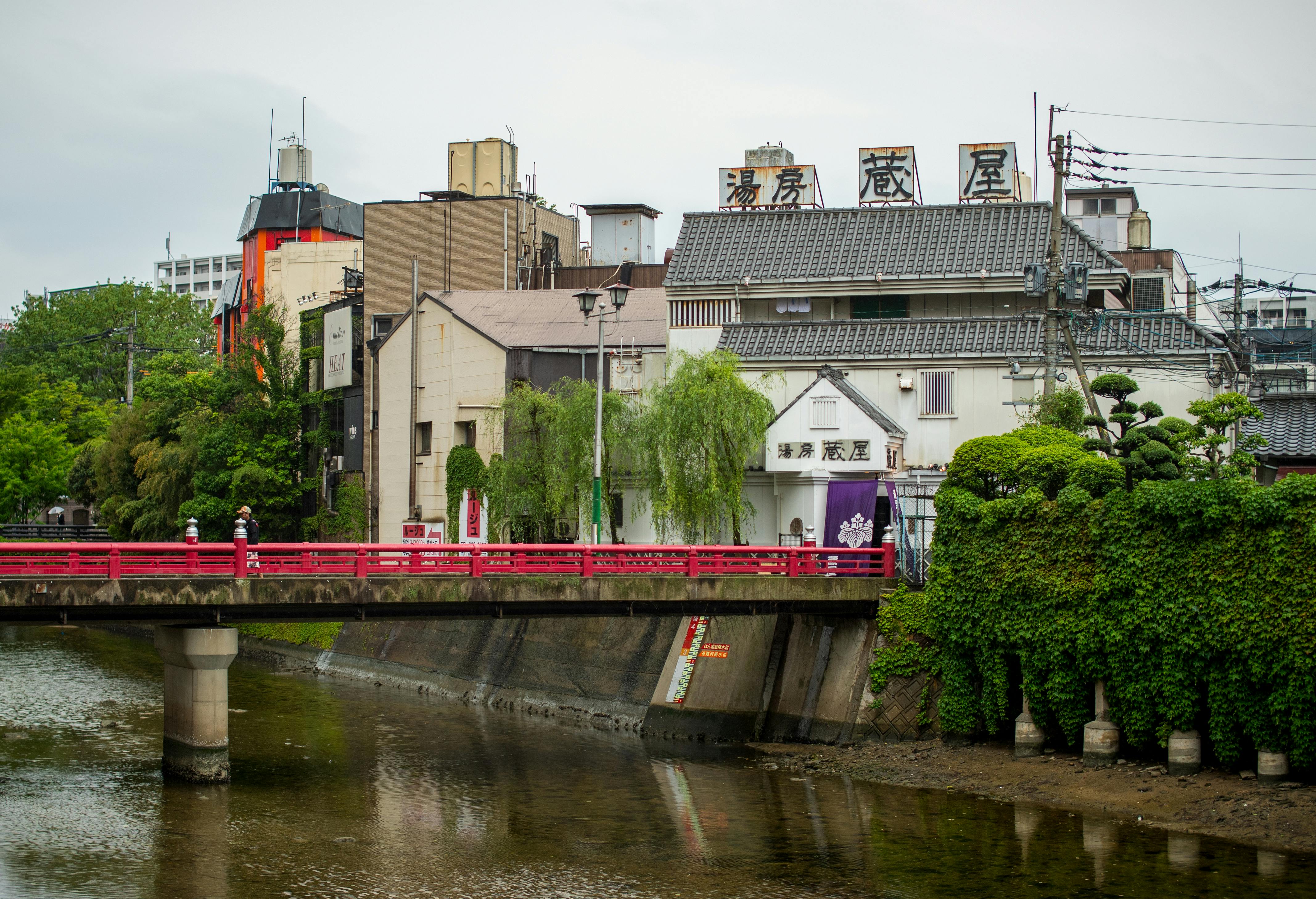 Scenic view of a red pedestrian bridge and historic buildings in Fukuoka, Japan.