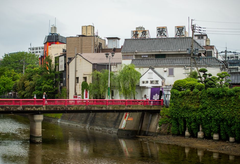 Scenic view of a red pedestrian bridge and historic buildings in Fukuoka, Japan.
