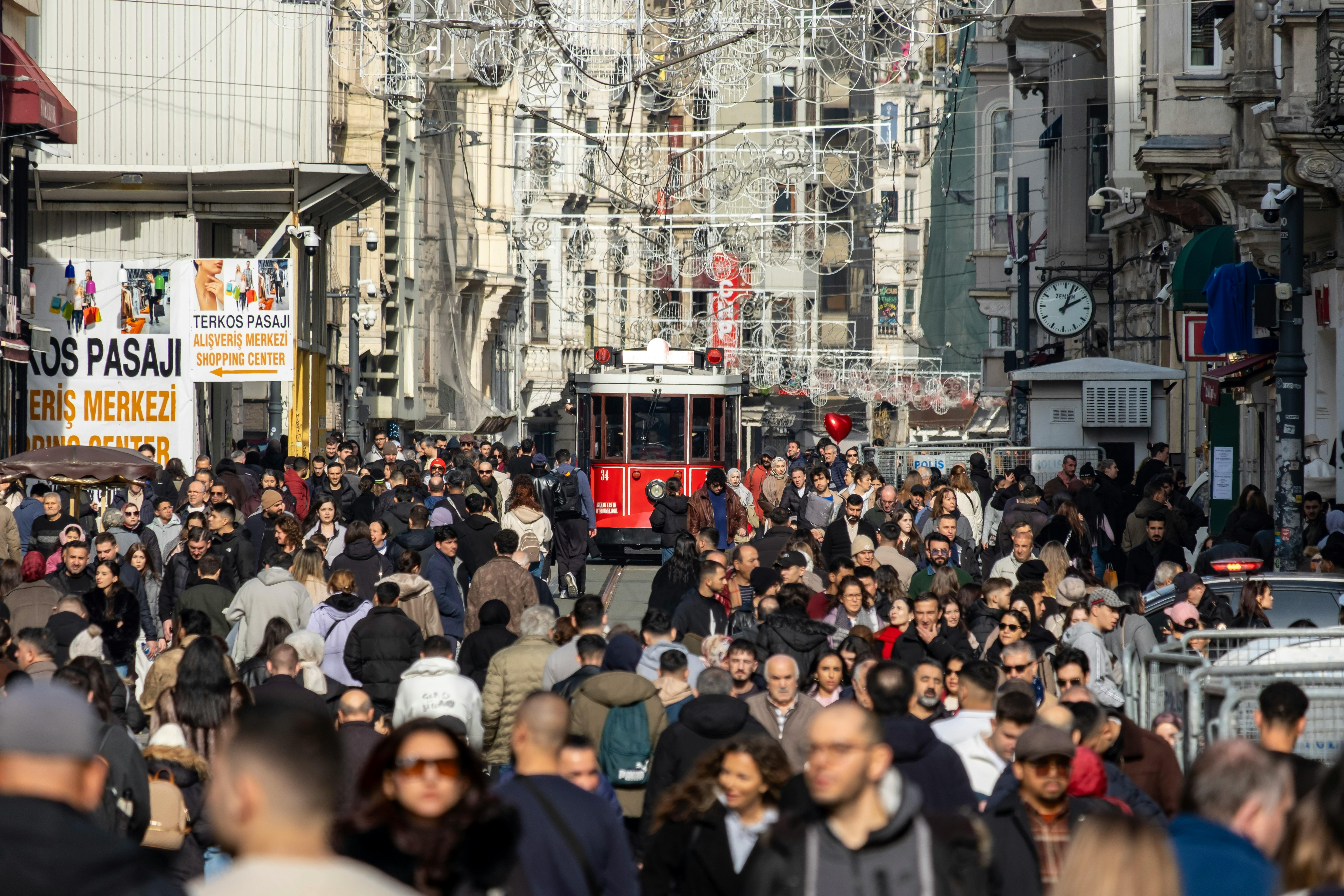 Crowded İstiklal Avenue in Istanbul featuring a historic red tram amid a diverse crowd.