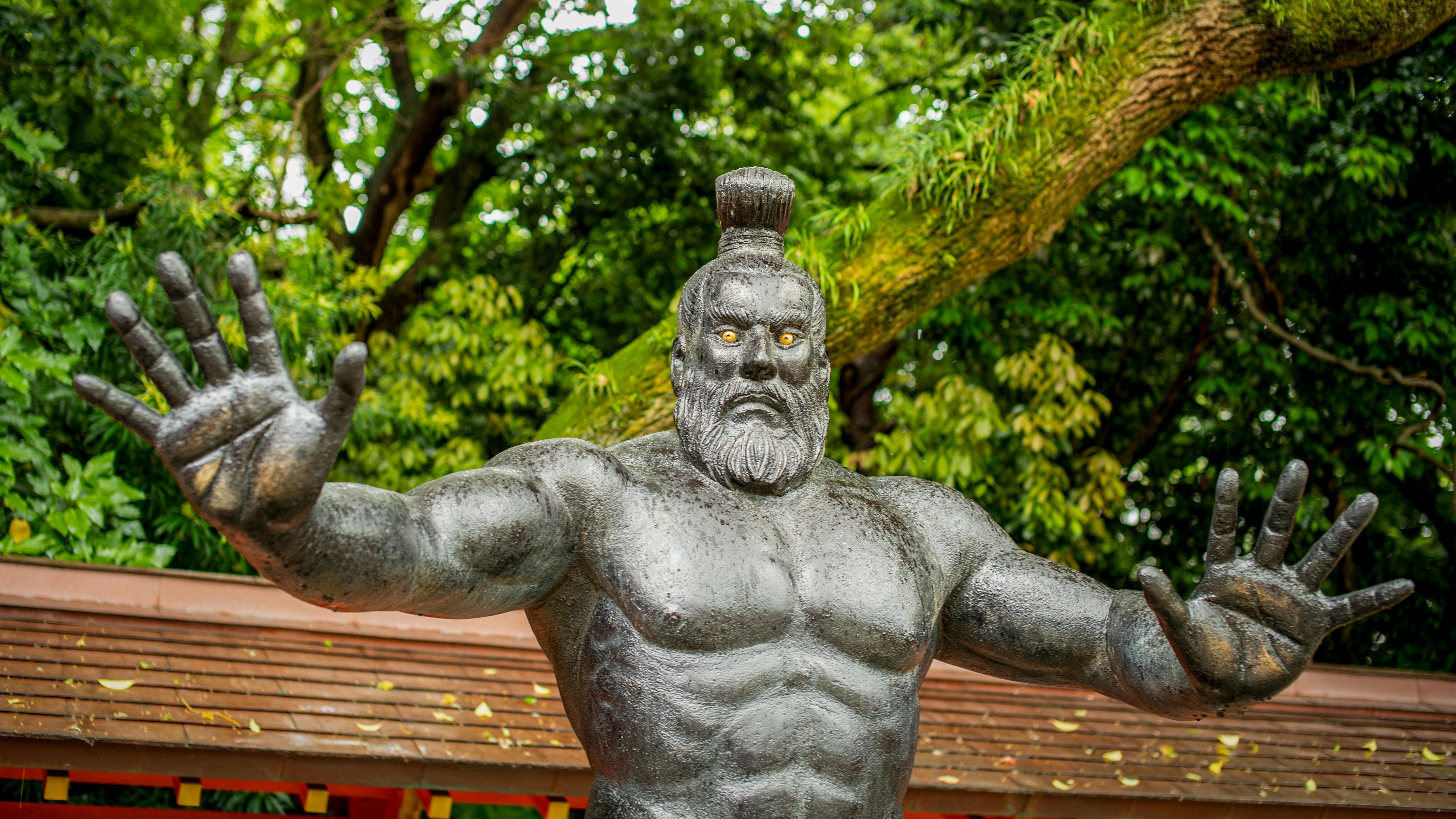 Striking sumo god statue in Fukuoka, Japan temple garden, amidst lush greenery.