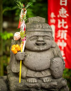 A detailed view of a cheerful stone statue in a Japanese temple courtyard in Fukuoka, Japan.