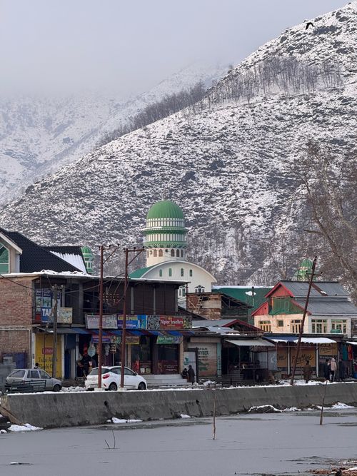 Free Scenic view of a snow-covered village near mountains with a mosque, showcasing winter tranquility. Stock Photo