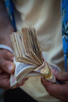 A person holding a large bundle of paper currency with both hands.