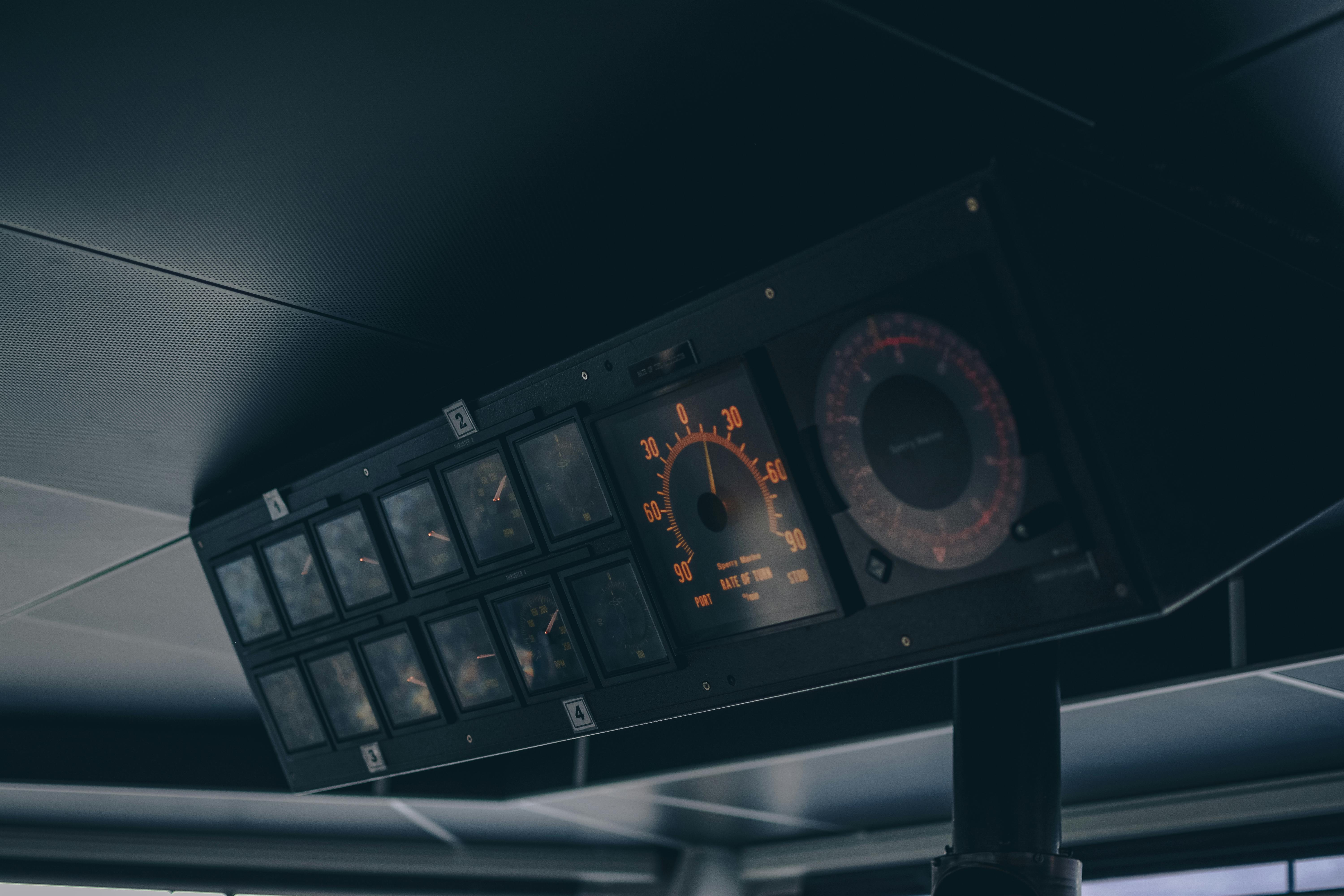 Close-up of a vintage boat cockpit featuring analogue speedometers and control panels in muted lighting.