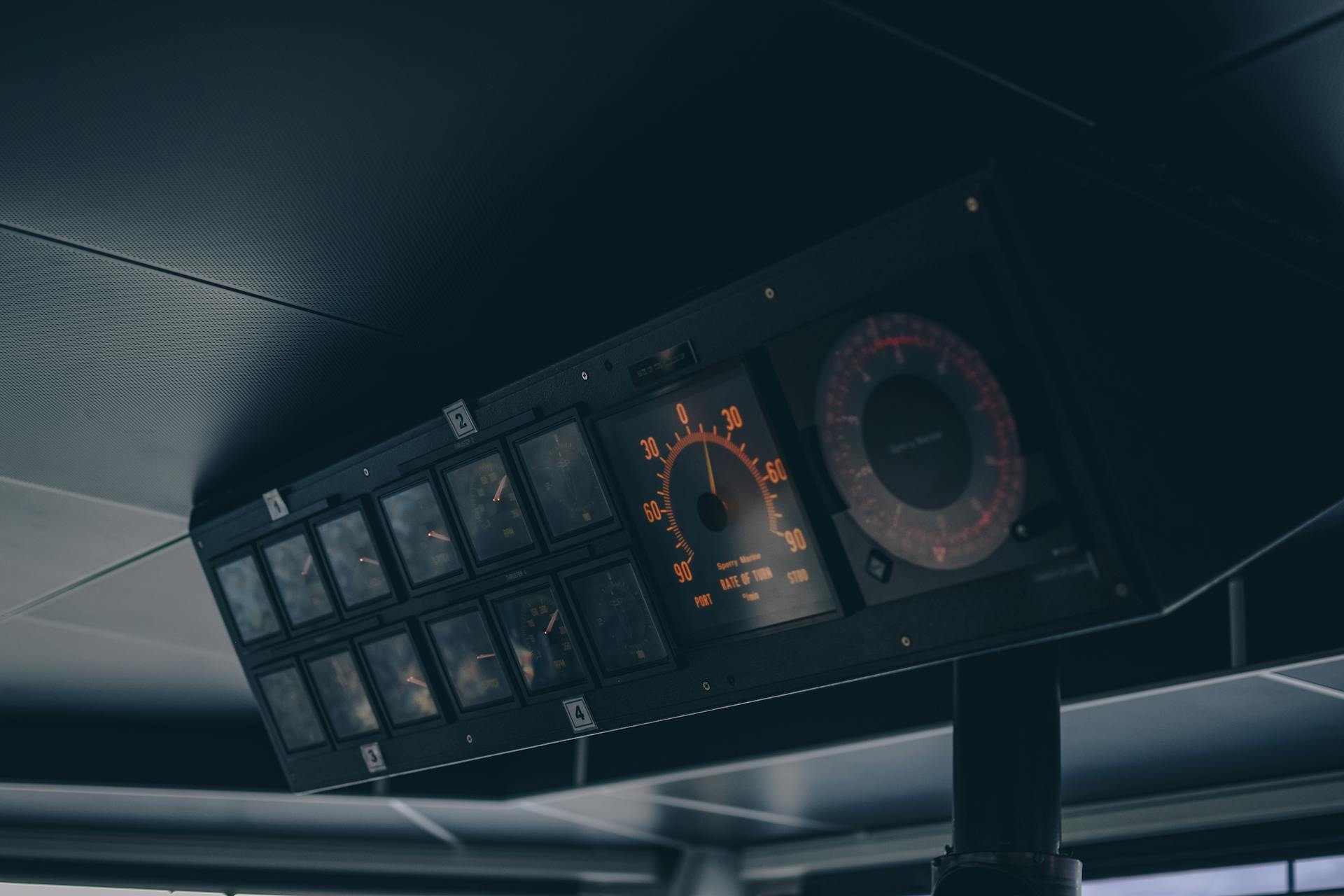 Close-up of a vintage boat cockpit featuring analogue speedometers and control panels in muted lighting.