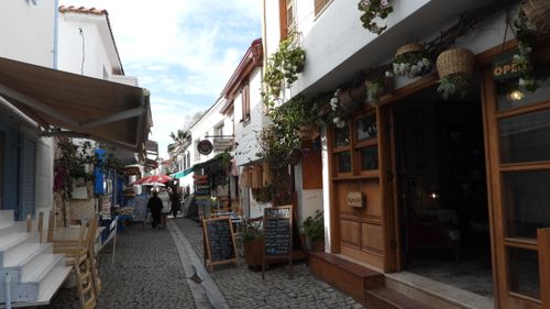 Free A picturesque, narrow street in a Turkish town lined with cafes and shops, perfect for exploration. Stock Photo