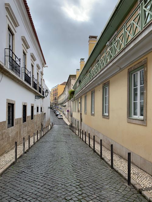 Free Scenic cobblestone street lined with historic buildings in Lisbon, Portugal. Perfect for travel photography. Stock Photo