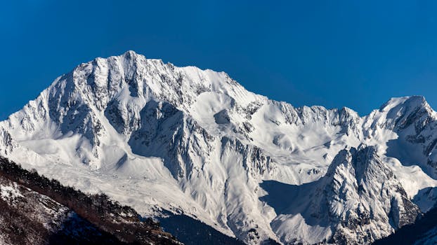 A breathtaking view of a pristine snow-covered mountain peak against a bright blue sky.