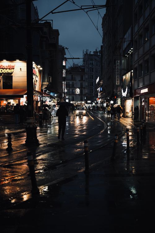 Free A rainy night street scene in Istanbul with glowing lights reflecting on wet roads, capturing urban life. Stock Photo