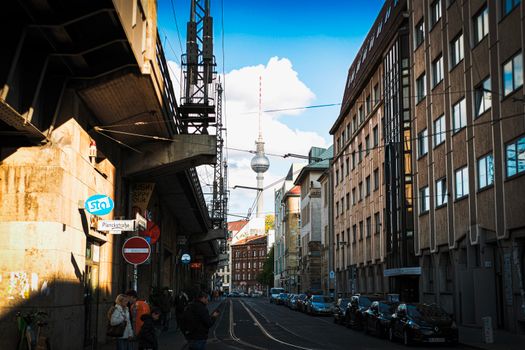 Street view in Berlin featuring the famous Fernsehturm tower with urban architecture and lively atmosphere.
