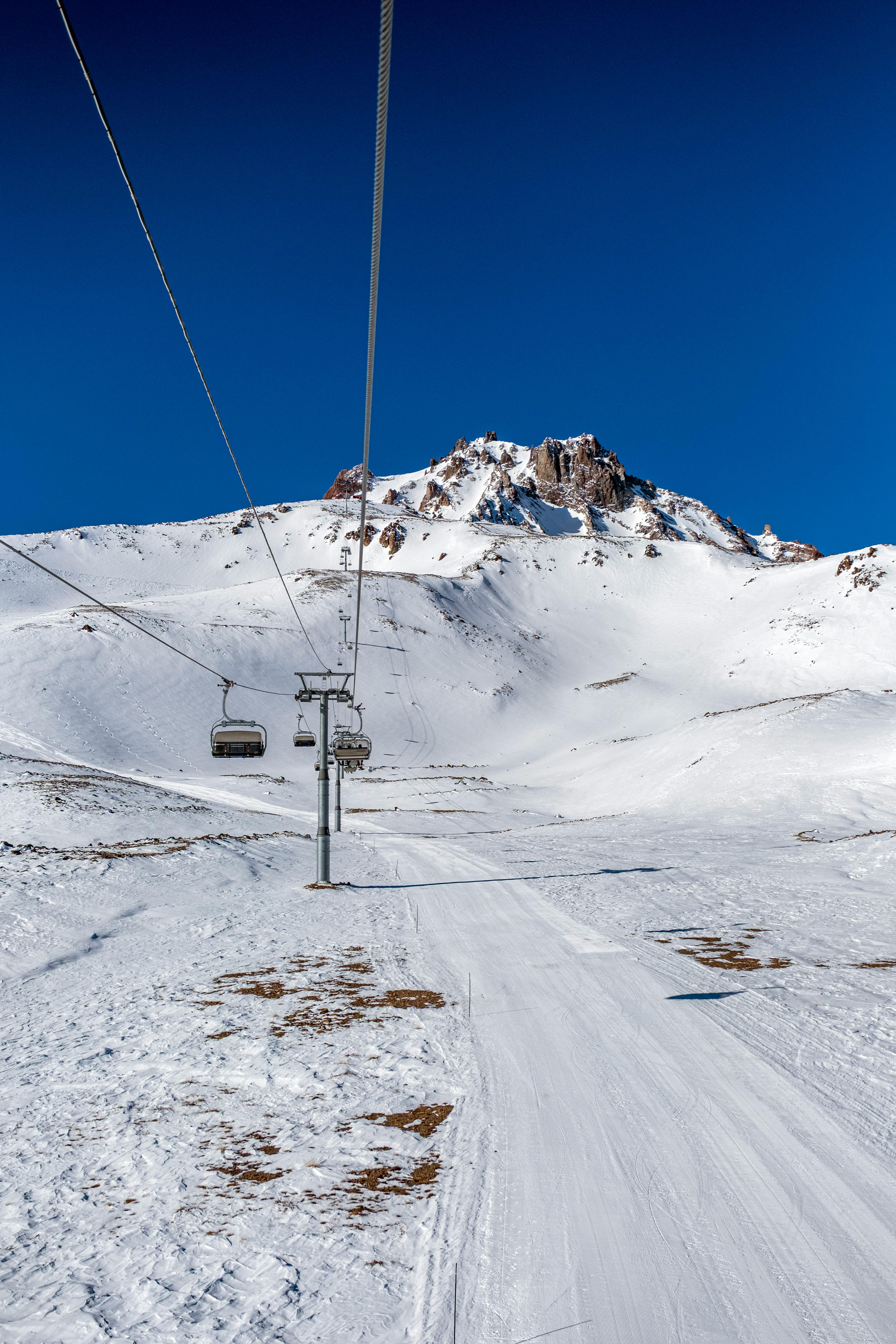 Captivating view of a ski lift ascending a snowy mountain under a vibrant blue sky.