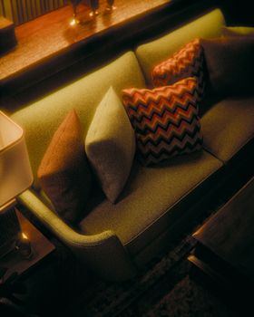 Inviting retro living room setup with vibrant pillows and warm lighting creating an intimate ambiance.