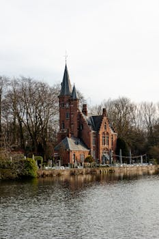 A picturesque Gothic building along a serene canal in Bruges, Belgium.