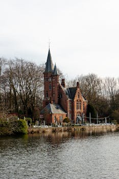 Historic brick house by a canal in Bruges, showcasing Flemish architecture.