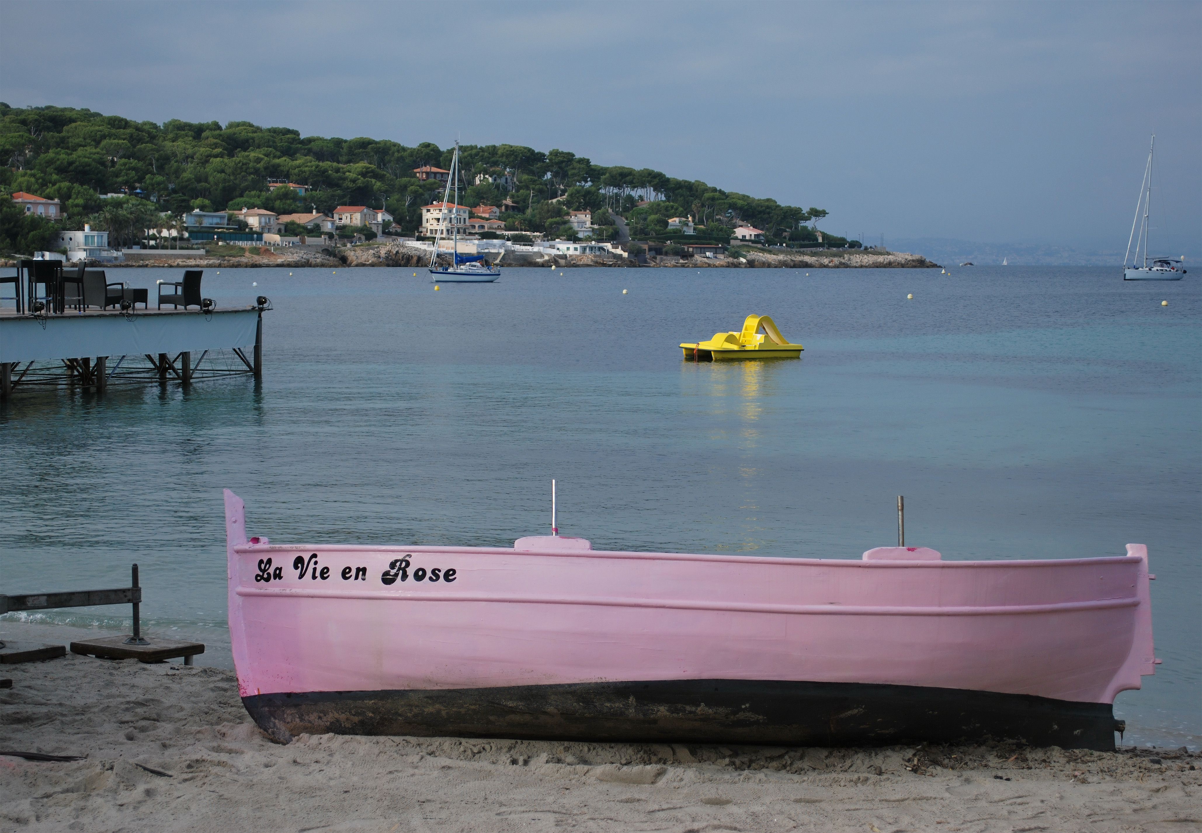 A charming pink boat titled 'La Vie en Rose' on a serene Antibes beach.