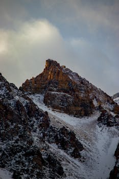 A stunning view of a snow-covered mountain peak during daylight with dramatic lighting.