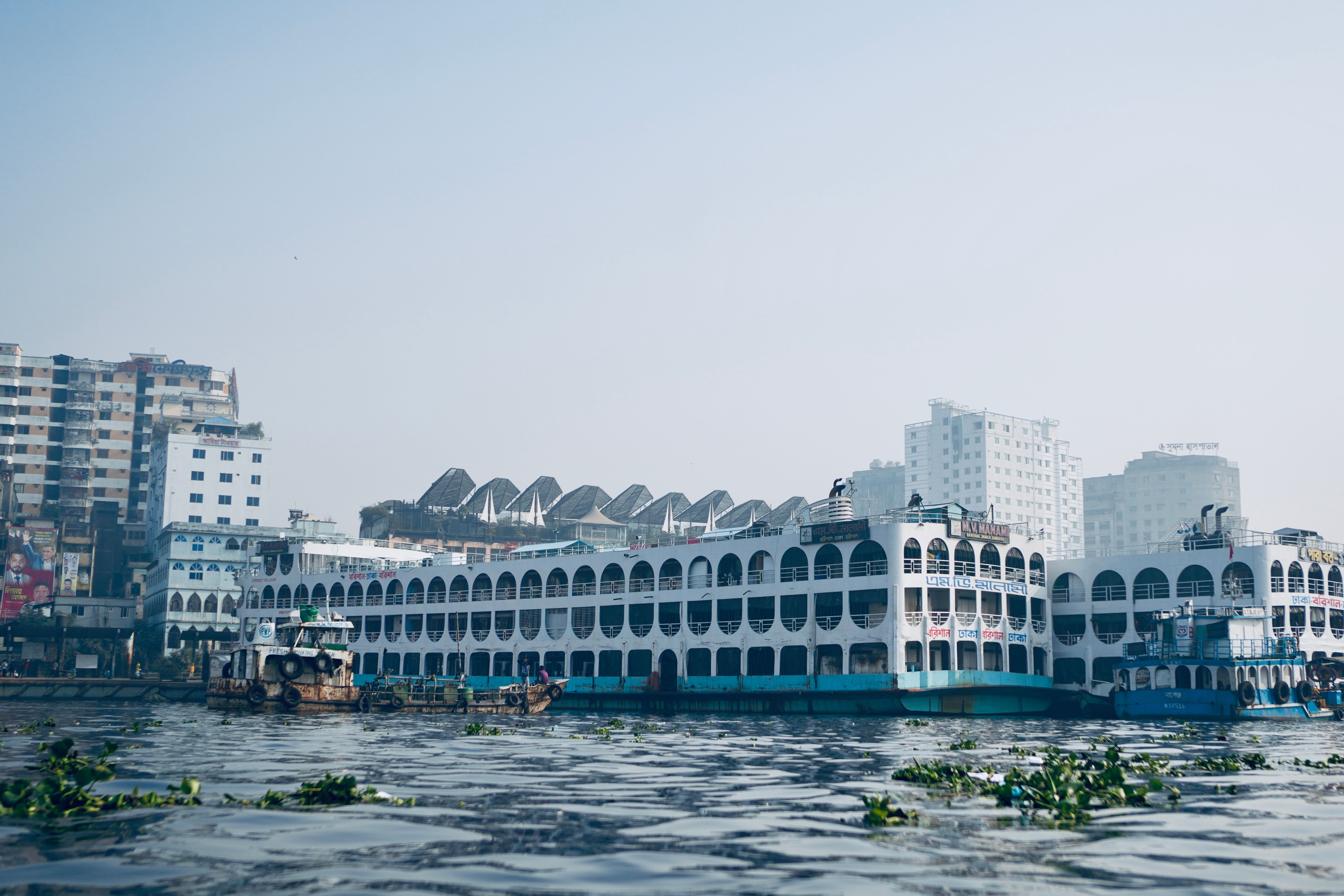 View of boats and modern architecture along the riverfront in Dhaka, Bangladesh.