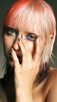 Artistic portrait featuring person with vibrant hair, metallic nails, and dramatic makeup.