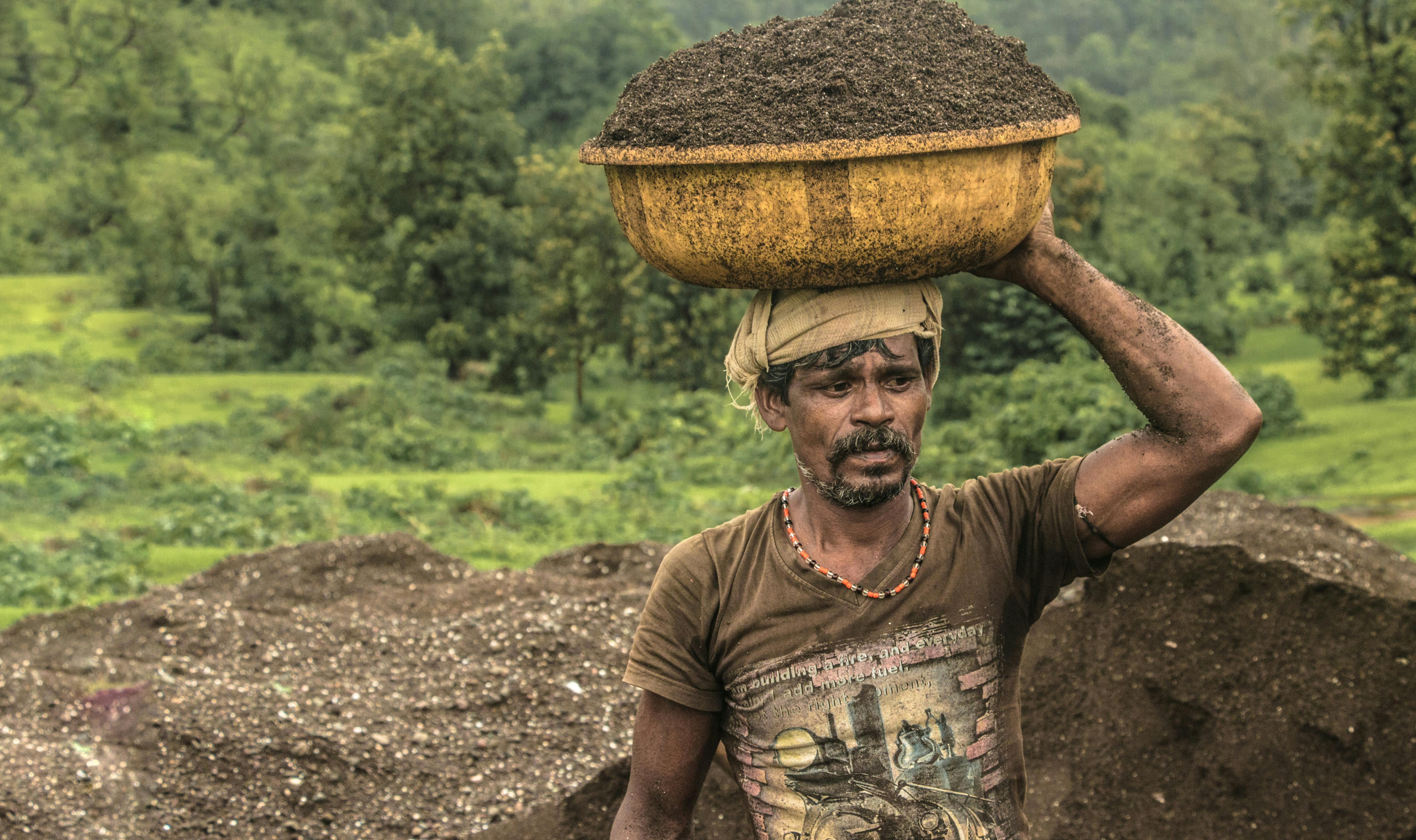 man carrying basin of soil on top of his head