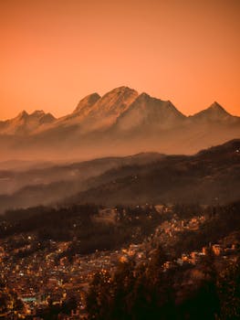 Stunning Andes mountain landscape at sunset with warm orange hues and a sprawling city below.