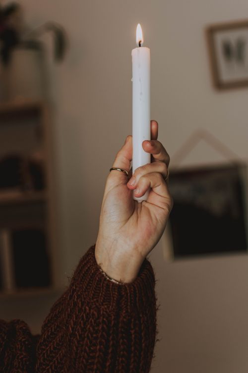 Free A close-up of a hand holding a lit candle, creating a warm and cozy ambiance. Stock Photo