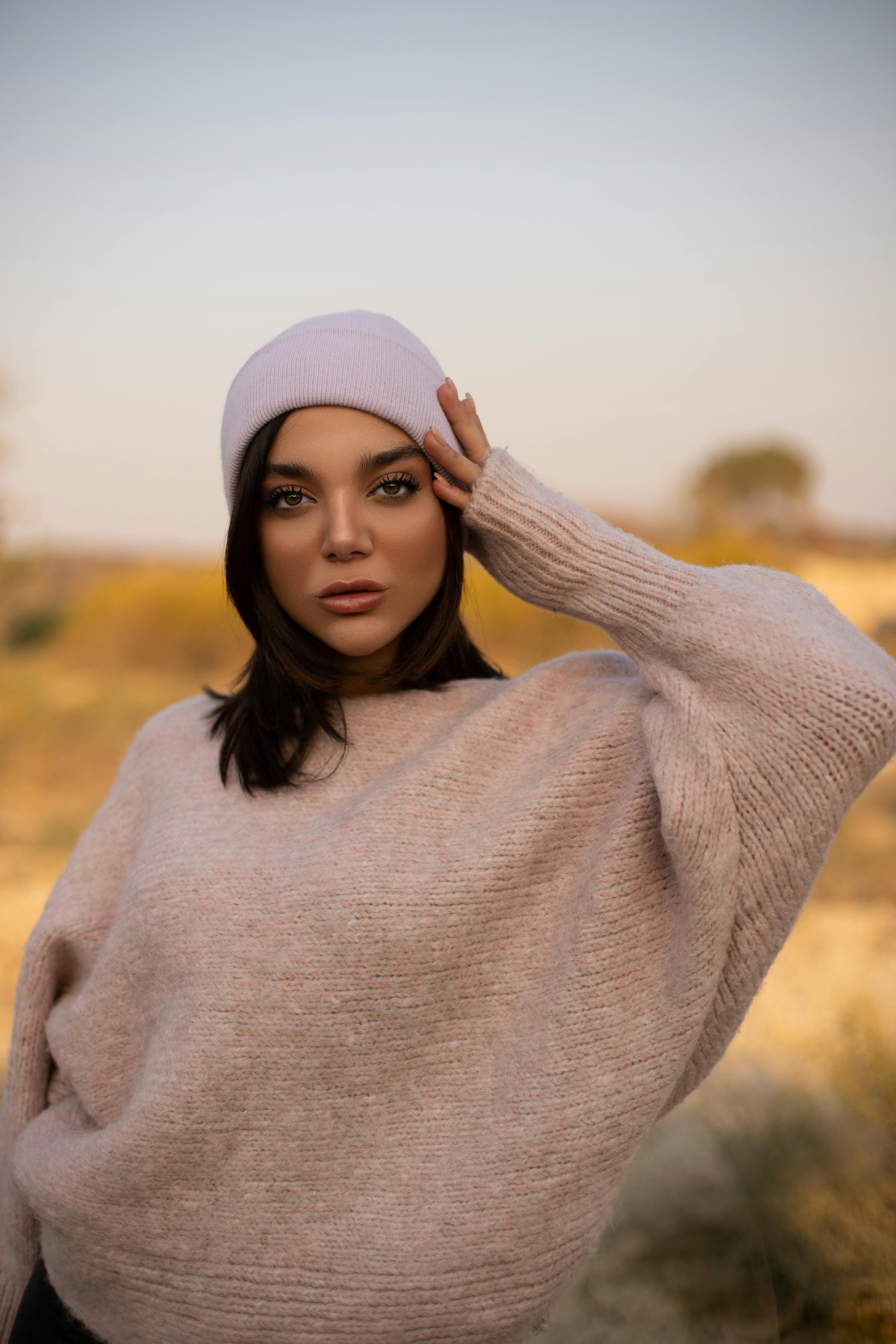 时尚的女人在户外摆放着针织毛衣和无檐帽